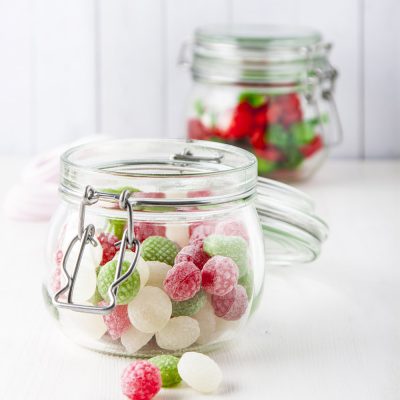 Sweet candies in glass jars on white wooden table